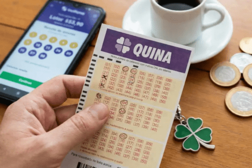 Pessoa segurando uma cartela de loteria da Quina, ao fundo uma xícara de café e moedas.
