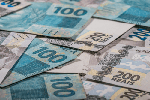 Notas de R$ 100 e R$ 200 sobrepostas.