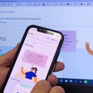 Uma pessoa segura um smartphone em primeiro plano, exibindo a página oficial do Prouni (Programa Universidade para Todos) no site do Governo Federal brasileiro (gov.br).