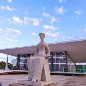 Fotografia da fachada do Supremo Tribunal Federal (STF) em Brasília, sob um céu azul claro com nuvens esparsas ao entardecer.