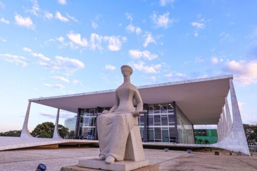 Fotografia da fachada do Supremo Tribunal Federal (STF) em Brasília, sob um céu azul claro com nuvens esparsas ao entardecer.