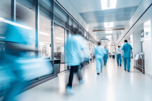 Corredor movimentado de um hospital moderno, com profissionais de saúde caminhando em desfoque de movimento, transmitindo agilidade e ambiente clínico.