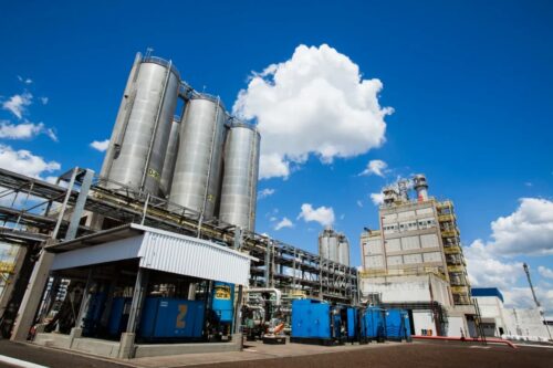 Fachada de indústria petroquímica com estruturas industriais, ilustrando crise e queda das ações da Braskem após prejuízo divulgado.