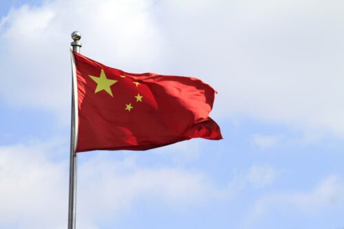 Bandeira da China tremulando; país projeta crescimento econômico entre 4,5% e 5% para 2026, a menor meta em décadas.