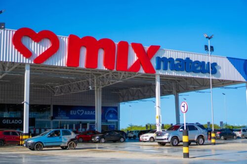 Fachada de loja do Grupo Mateus com logotipo Mix Mateus e estacionamento com carros na entrada do supermercado.