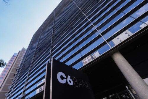 Fachada de prédio do C6 Bank em área urbana, após suspensão do consignado pelo INSS.