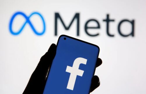 Celular com logo do Facebook em frente ao logotipo da Meta ao fundo, representando a empresa de tecnologia.