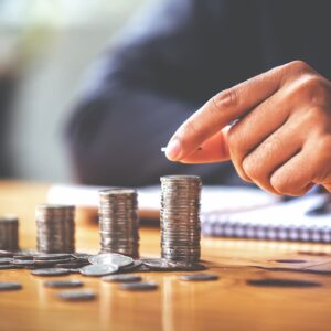 ão empilhando moedas em pilhas crescentes sobre mesa, representando planejamento financeiro e investimentos.