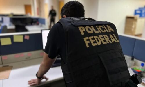 Agente da Polícia Federal em escritório durante operação contra tráfico e lavagem de dinheiro em vários estados.