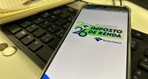 Celular com tela do Imposto de Renda 2026 sobre teclado, destacando app da Receita Federal para declaração.