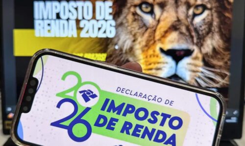 Celular exibe tela do Imposto de Renda 2026 com leão ao fundo, símbolo da Receita Federal no Brasil.