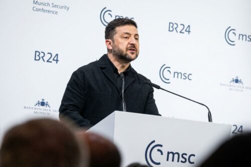 Fotografia de meio corpo do presidente da Ucrânia, Volodymyr Zelensky, discursando em um púlpito branco.