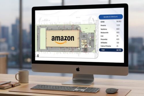 Fotografia de um escritório moderno com um monitor em primeiro plano exibindo a planta baixa de um galpão logístico da Amazon. A