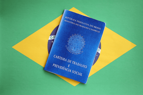 Carteira de trabalho e previdência social do Brasil sobre fundo com a bandeira do Brasil. Documento oficial do Ministério do Trabalho.