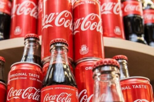 Uma exibição criativa de produtos Coca-Cola em uma prateleira de supermercado.