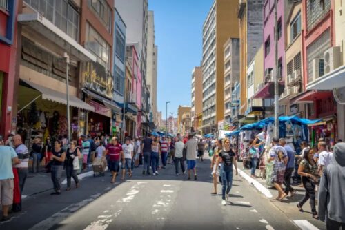 Vista ao nível da rua de uma área comercial popular e movimentada, em São Paulo.