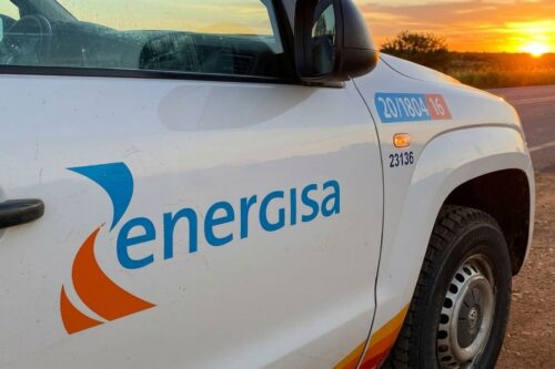 Logotipo da Energisa estampado na lateral de um veículo utilitário branco durante o pôr do sol.