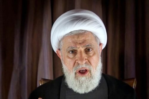 Retrato em close do líder do Hezbollah, falando expressivamente em frente a uma cortina marrom escura.