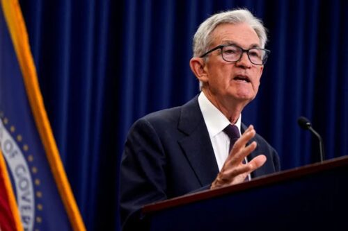 Retrato de Jerome Powell, presidente do Federal Reserve, falando em um púlpito.