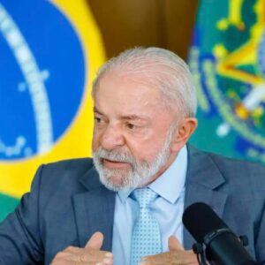 O presidente Luiz Inácio Lula da Silva falando em um microfone durante uma transmissão ou entrevista.