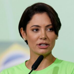 Fotografia em close-up de Michelle Bolsonaro falando ao microfone.