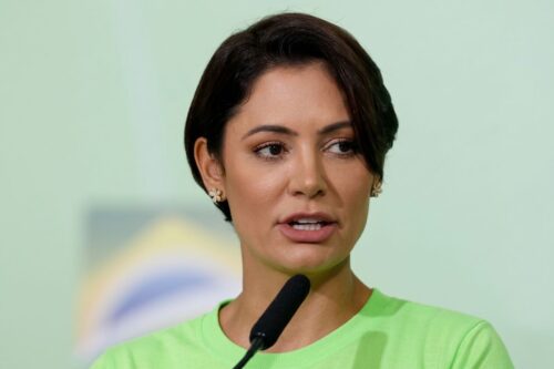 Fotografia em close-up de Michelle Bolsonaro falando ao microfone.