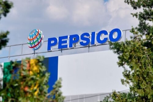 Fachada de uma unidade da PepsiCo com o logotipo azul em destaque no topo de uma estrutura metálica, acompanhado pelo ícone do globo colorido.