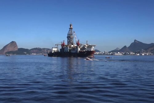 Uma grande plataforma de petróleo ou navio-sonda da Petrobras navegando nas águas calmas da Baía de Guanabara, no Rio de Janeiro.