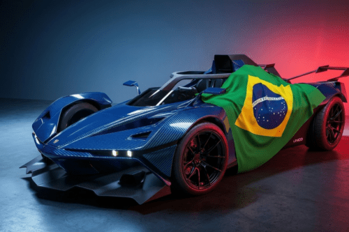 Uma fotografia de estúdio em alta resolução de um supercarro de pista com design futurista e aerodinâmico. O veículo possui carroceria em fibra de carbono azul brilhante com textura visível. Uma bandeira do Brasil está estendida sobre a lateral e o cockpit do carro. O ambiente é um estúdio escuro com iluminação dramática em tons de azul e vermelho ao fundo, destacando as linhas agressivas, o aerofólio traseiro e os pneus largos de alto desempenho. A palavra "UNICO" é visível na parte inferior lateral do veículo.