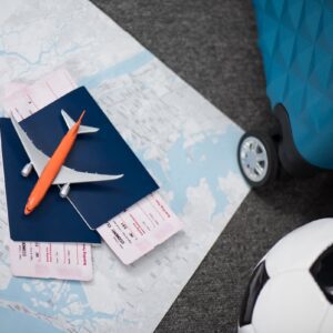 Passagens, mala, mapa e bola de futebol sobre fundo de viagem, representando quanto custa ir para a Copa do Mundo 2026.