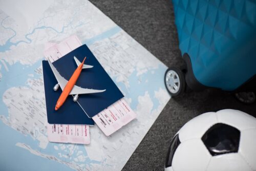Passagens, mala, mapa e bola de futebol sobre fundo de viagem, representando quanto custa ir para a Copa do Mundo 2026.