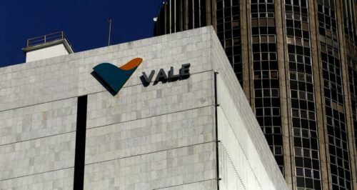 Fachada de prédio da Vale com logotipo da empresa em destaque, em frente a edifícios corporativos sob céu azul.