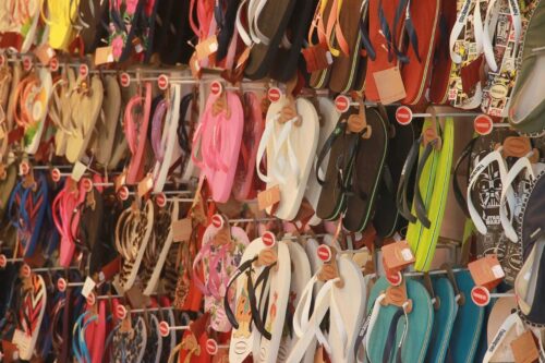 Uma parede de exibição repleta de chinelos Havaianas de diversas cores e estampas, pendurados em ganchos organizados.
