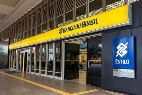 Fachada de uma agência do Banco do Brasil Estilo. Uma longa testeira amarela com o logotipo e o nome do banco percorre o topo da entrada.