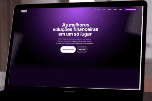 Vista diagonal de um notebook MacBook aberto exibindo a página inicial de um site com fundo roxo escuro gradiente. No centro da tela, destaca-se o texto em letras grandes e brancas: "As melhores soluções financeiras em um só lugar". Abaixo, um parágrafo menor explica que a Best Franquias conecta empreendedores a um ecossistema financeiro. Há dois botões arredondados na parte inferior central: um branco onde se lê "Seja um franqueado" e outro vazado escrito "Saiba mais". No canto superior esquerdo está o logotipo da marca "best" e, no canto superior direito, o menu de navegação e um botão roxo repetindo "Seja um franqueado". No canto inferior direito da tela, há um pequeno ícone verde do WhatsApp.