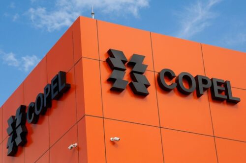 Close-up do topo de um edifício com painéis laranjas exibindo o logotipo preto da Copel.