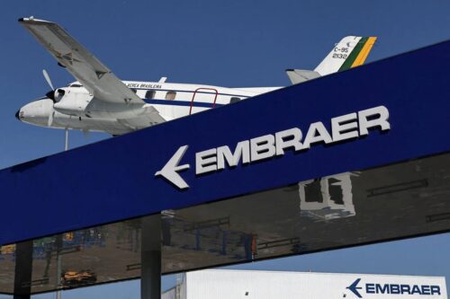 Placa azul com o logotipo da Embraer em letras brancas em destaque.