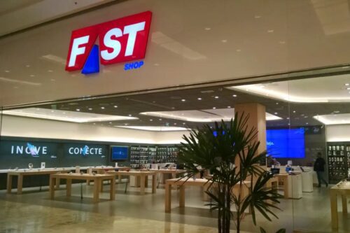 Fachada da loja Fast Shop vista de fora. O logotipo da marca está em destaque em um letreiro vermelho e branco acima da entrada.