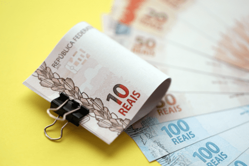 Vista aproximada de notas de dinheiro em reais brasileiros em grande quantidade em amarelo. Pilha de moeda real do Brasil