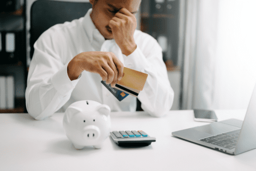 Em dívida financeira, homem sentado, segurando cartão de crédito, estressado