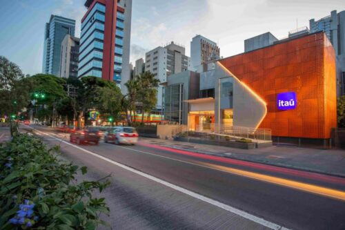 Fachada de uma agência moderna do banco Itaú ao entardecer.