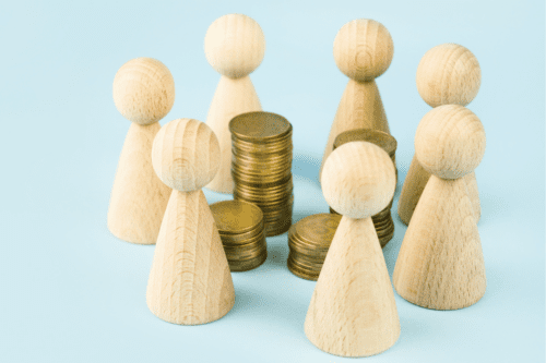 Conceito de negócio. Figuras de madeira de pessoas em pé ao redor de moedas em um fundo azul. Ideia de negócio.