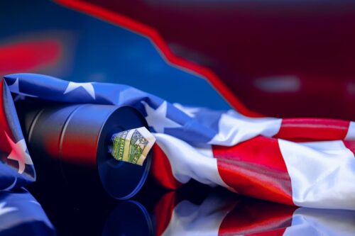 Bandeira americana e nota de dólar sobre fundo preto, simbolizando a economia dos EUA e o preço da gasolina.