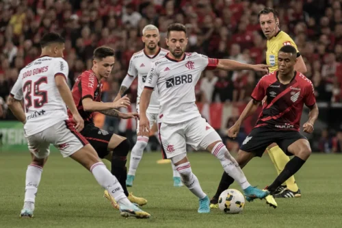 Jogadores de Athletico e Flamengo disputam bola em partida pelo Brasileirão na Arena da Baixada.