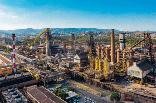 Vista aérea de uma siderúrgica industrial com fornos e tubulações, da CSN.