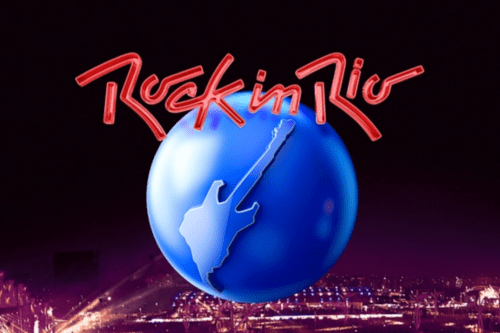 Logotipo oficial do festival Rock in Rio centralizado sobre uma vista aérea noturna do evento iluminado. O logo consiste em uma grande esfera azul brilhante com a silhueta de uma guitarra estilizada em seu centro. Acima da esfera, está escrita a frase "Rock in Rio" em uma fonte vermelha manuscrita e marcante. O fundo da imagem mostra as luzes da Cidade do Rock e o público sob um céu escuro.