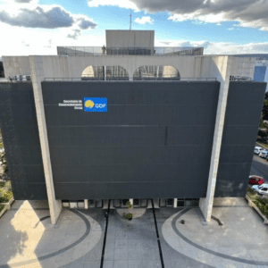 Foto aérea da fachada do edifício da Secretaria de Desenvolvimento Social (SEDES) do Distrito Federal, com o logotipo do GDF em destaque na parede cinza escura.