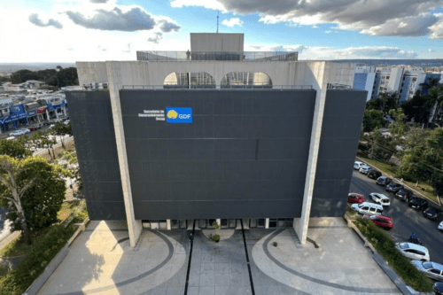 Foto aérea da fachada do edifício da Secretaria de Desenvolvimento Social (SEDES) do Distrito Federal, com o logotipo do GDF em destaque na parede cinza escura.