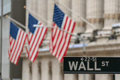 Placa “WALL ST” de Wall Street e Broadway sobre bandeiras nacionais americanas.