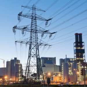 Linhas de transmissão de energia e usina elétrica ao entardecer, setor de infraestrutura e geração de energia.